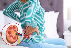 mujer sentada sobre la cama con dolor en los riñones
