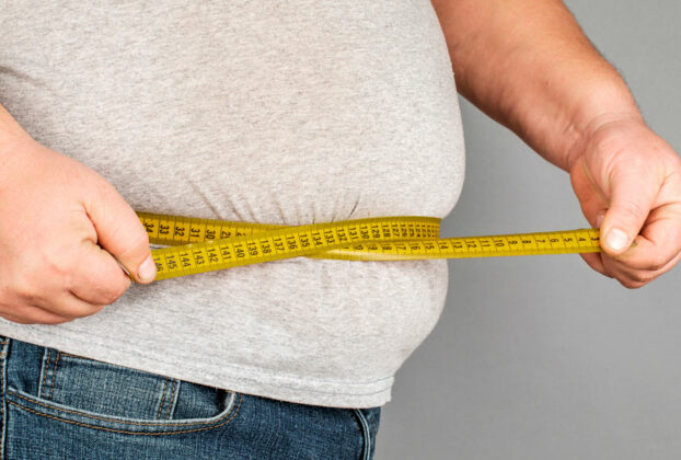 persona obesa midiendo su cintura