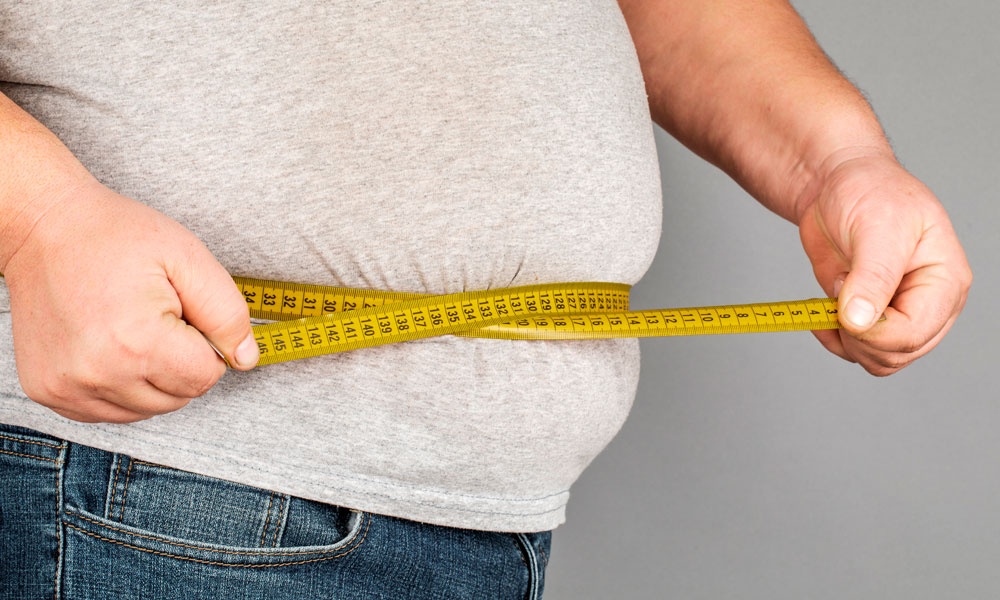 persona obesa midiendo su cintura