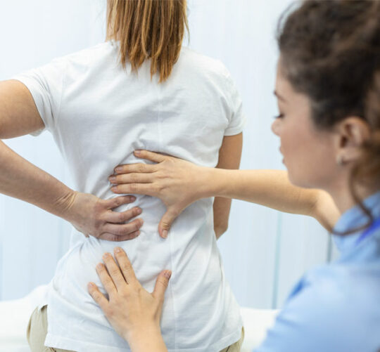 doctora revisando columna vertebral de paciente femenina