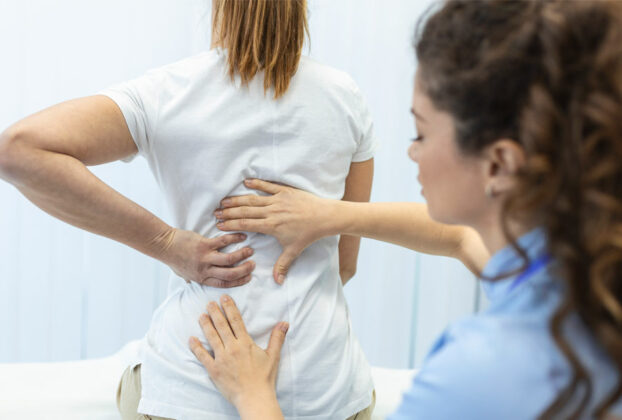 doctora revisando columna vertebral de paciente femenina
