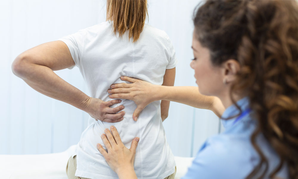 doctora revisando columna vertebral de paciente femenina