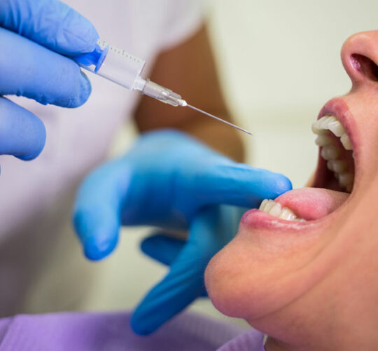 Dentista inyectando a paciente