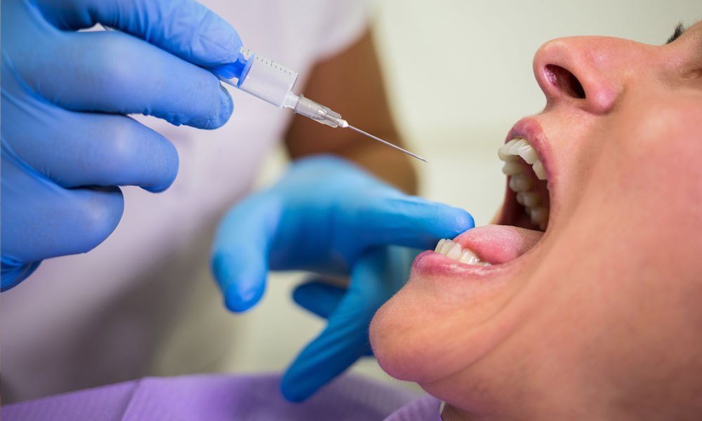 Dentista inyectando a paciente